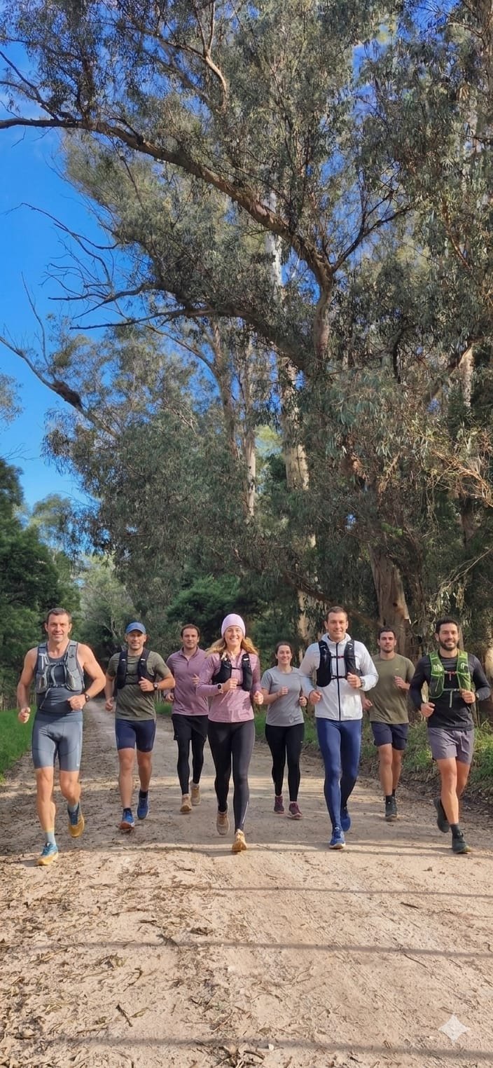Grupo de corredores entrenando juntos por un camino de tierra entre los árboles